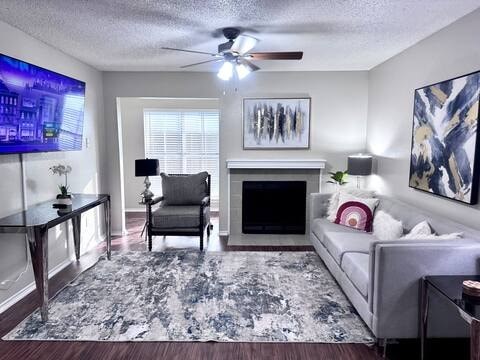 A living room with a grey couch, a black chair, a fireplace, and a painting on the wall.