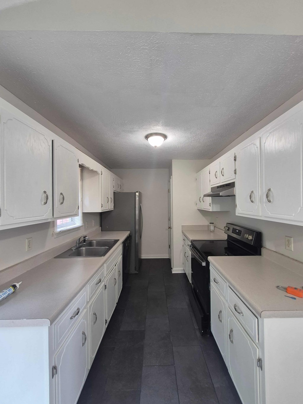 A kitchen with white cabinets and black appliances.