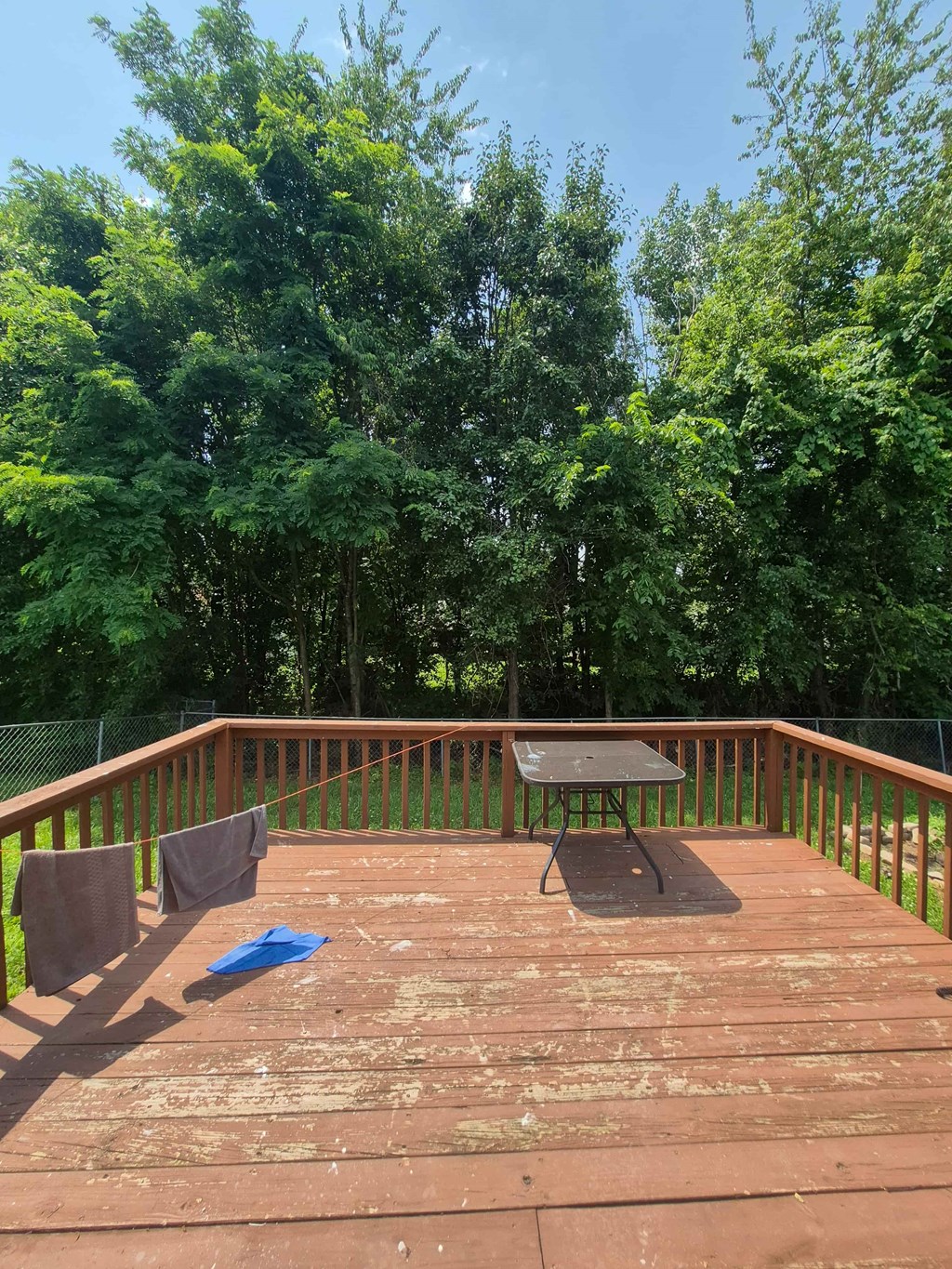 A wooden deck with a table and clothes hanging.