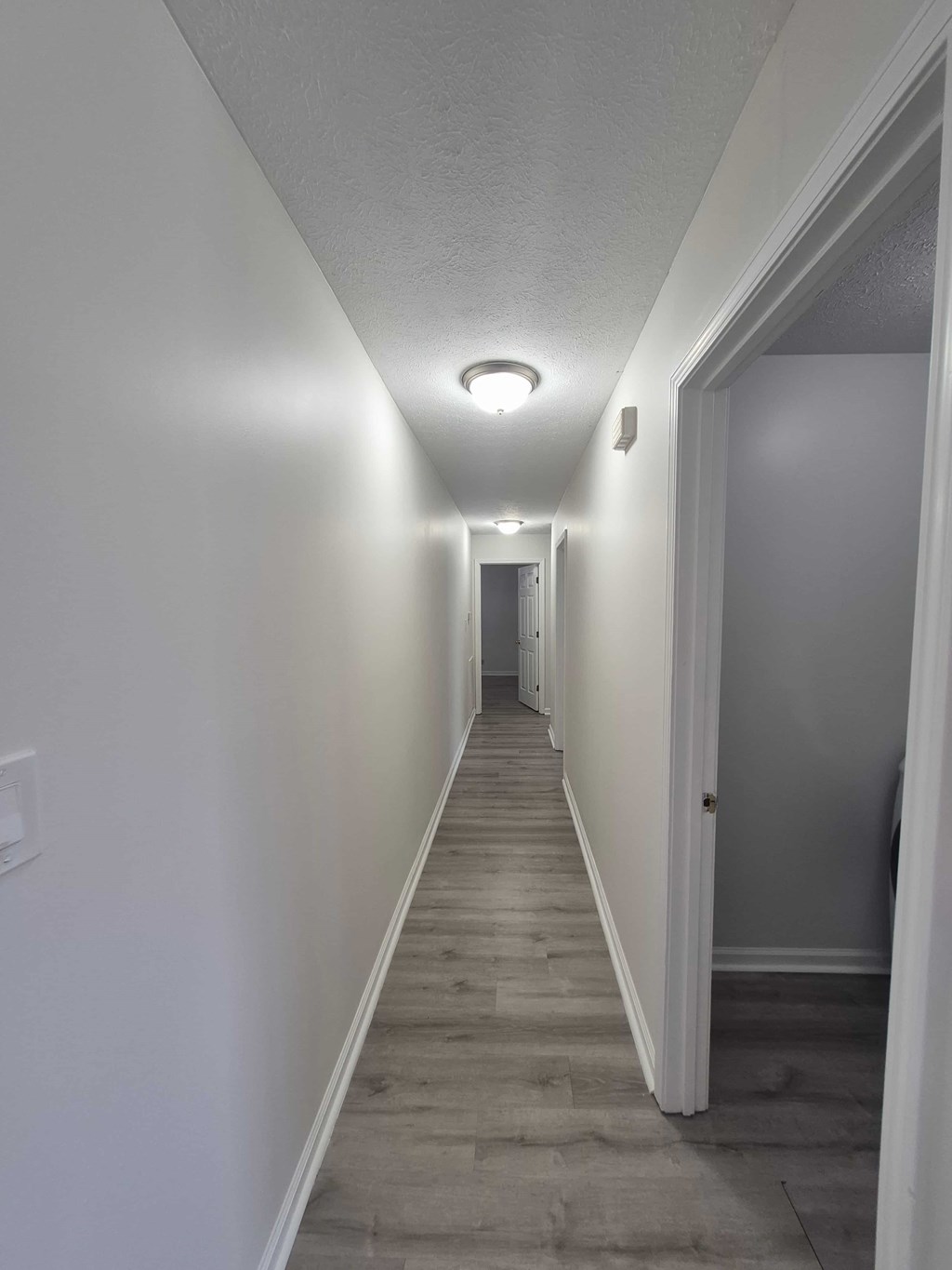 A long hallway with white walls and wood flooring.