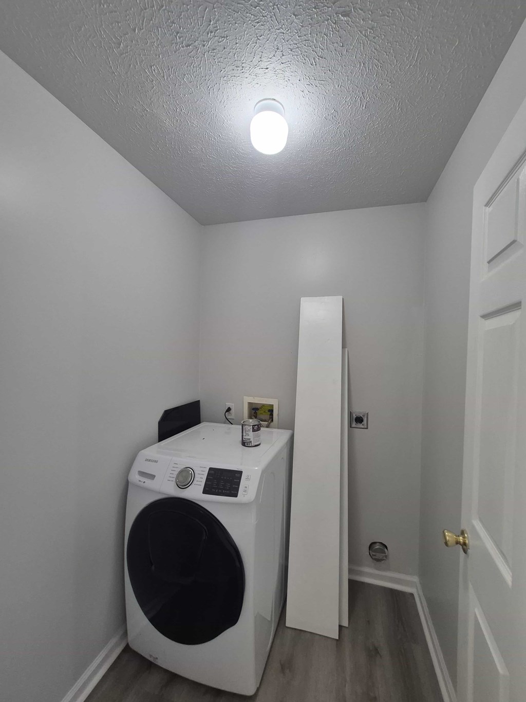 A white washing machine in a small room with a door on the right.