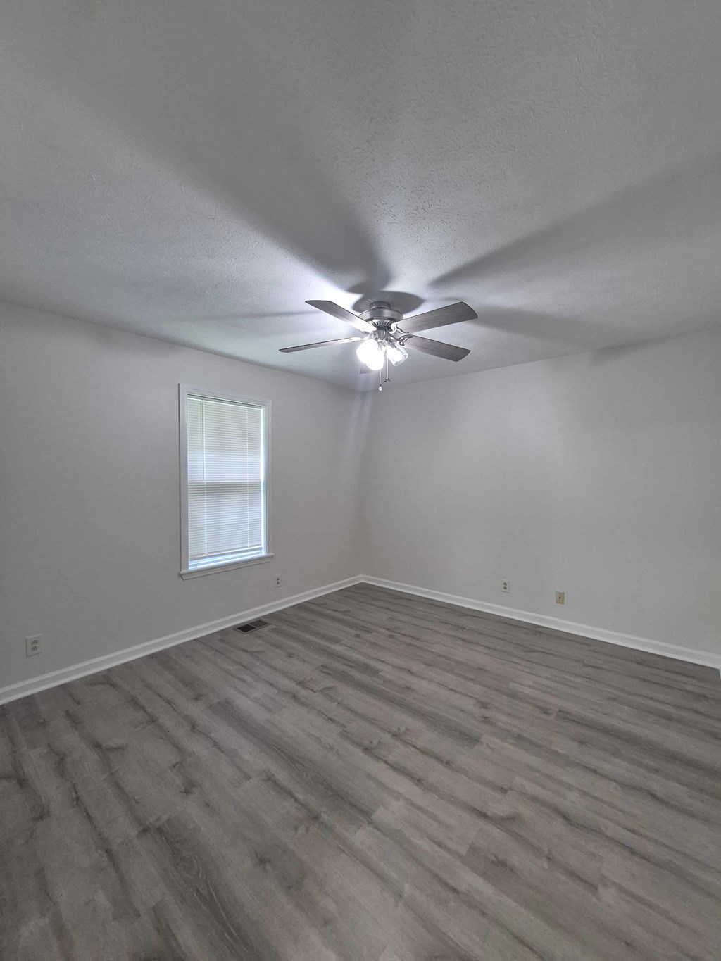 A room with a ceiling fan and a window.
