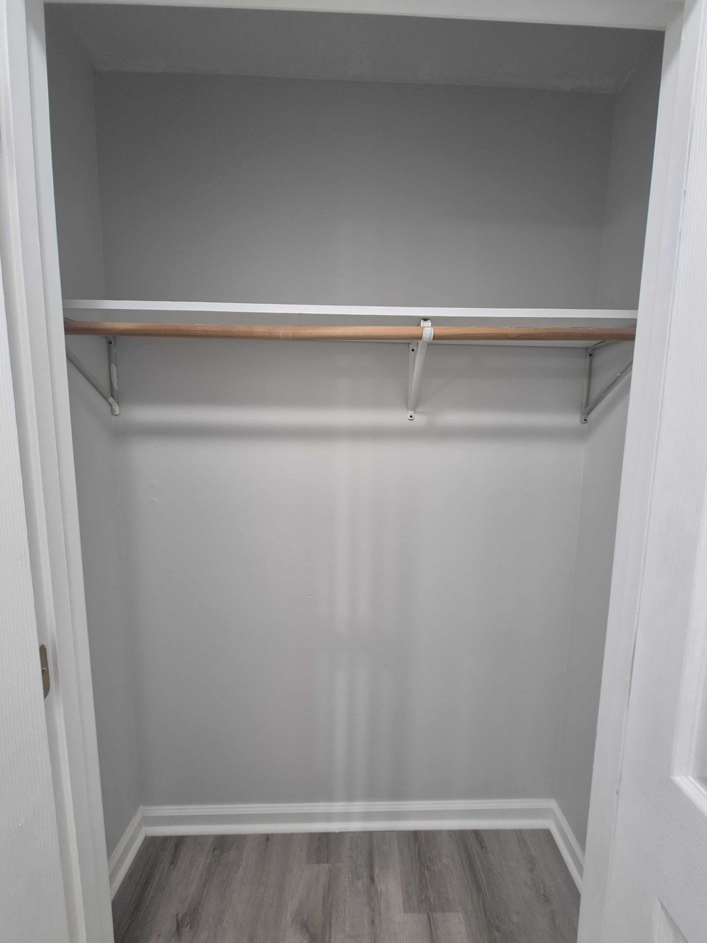 A white closet with a shelf and a grey floor.