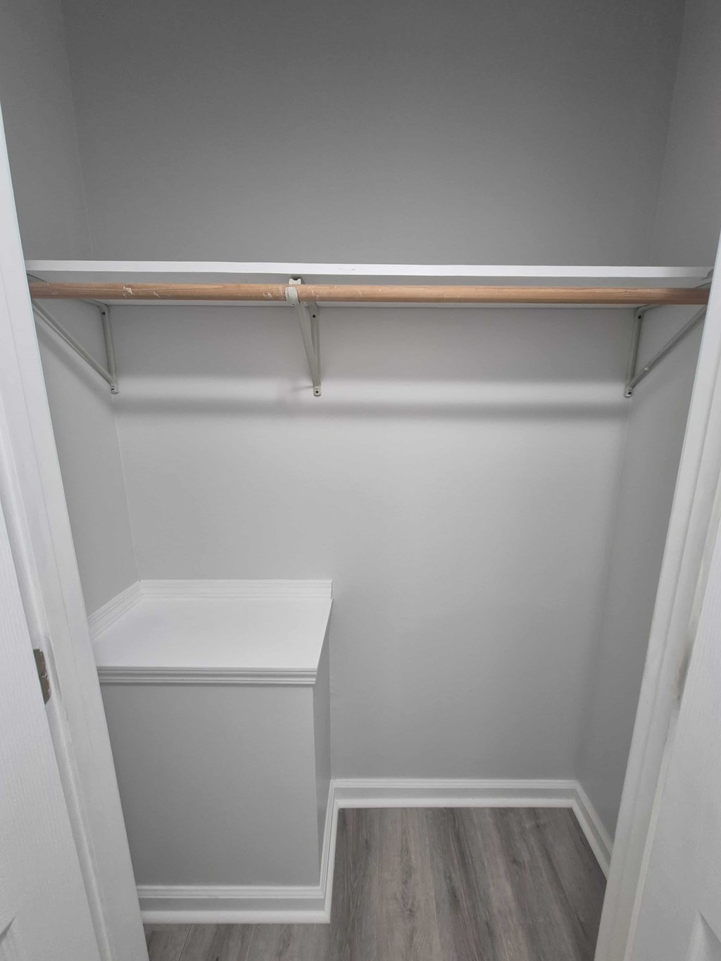 A small white closet with a shelf and a white box on the floor.