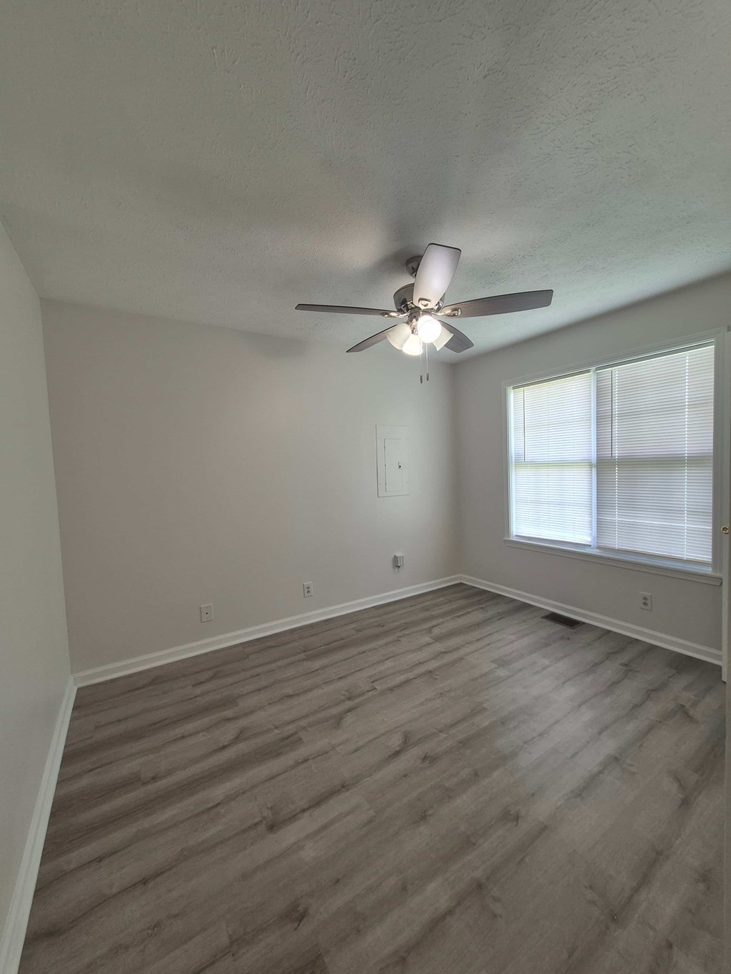 A room with a ceiling fan and wooden flooring.