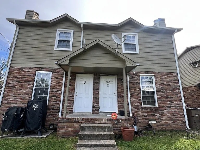 A house with a front porch and a satellite dish on the roof.