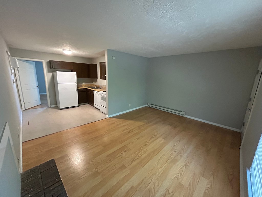 A kitchen with white appliances and wooden floors.