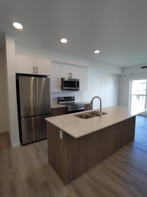A modern kitchen with a stainless steel refrigerator and wooden cabinets.