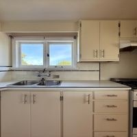 A kitchen with white cabinets and a window.