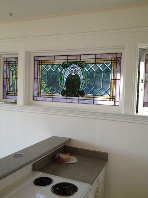A kitchen with a stove and a window with a stained glass design.