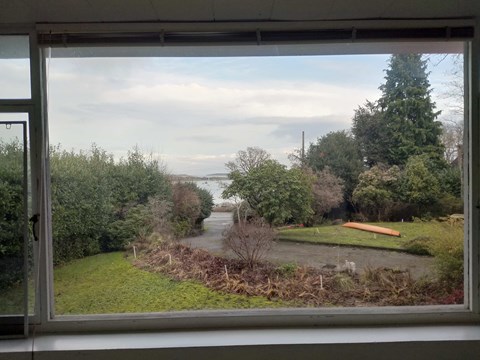 A view from a window looking out to a rural landscape with a river and trees.