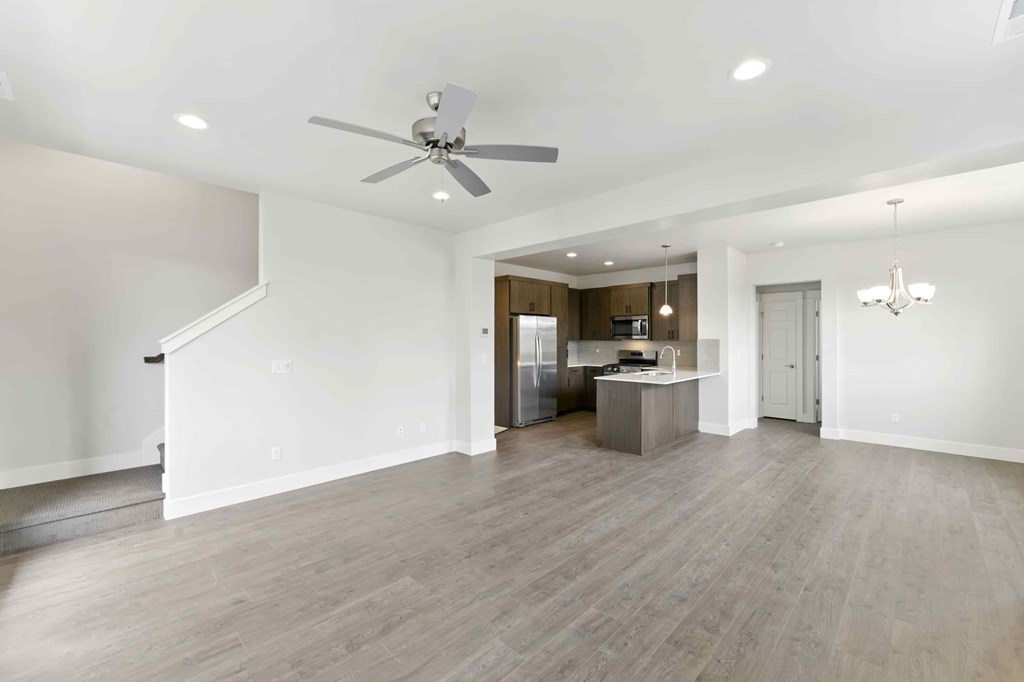 A spacious living room with a kitchen in the background.