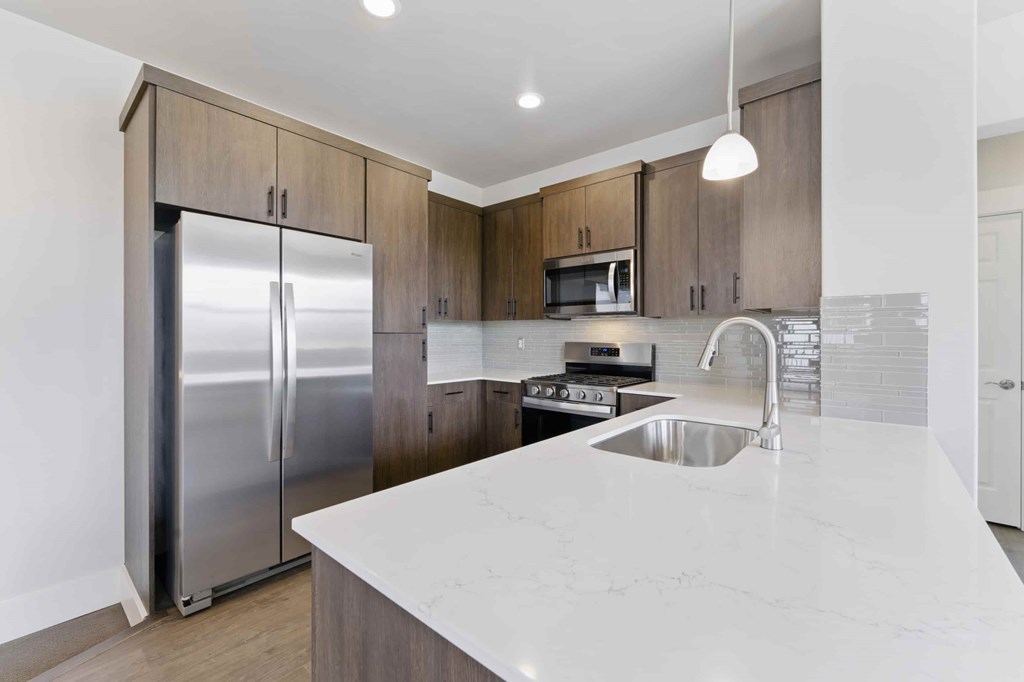 A modern kitchen with a stainless steel refrigerator and a marble countertop.