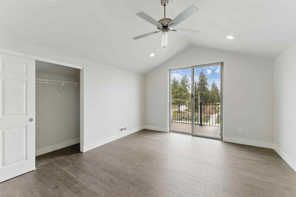 A room with a ceiling fan and sliding glass doors.