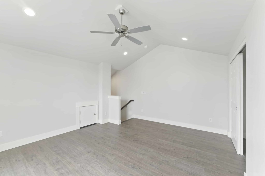 A room with a ceiling fan and light fixture, and a door on the right.