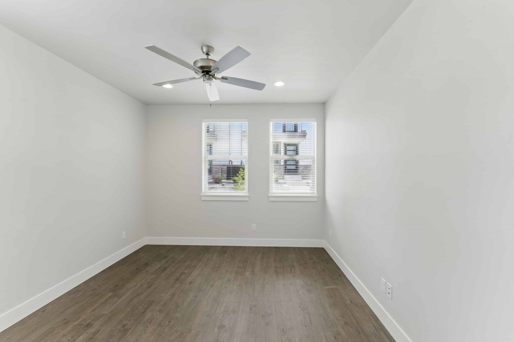 A room with a ceiling fan and a window with blinds.