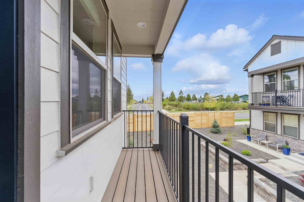 A balcony with a black railing and brown decking.