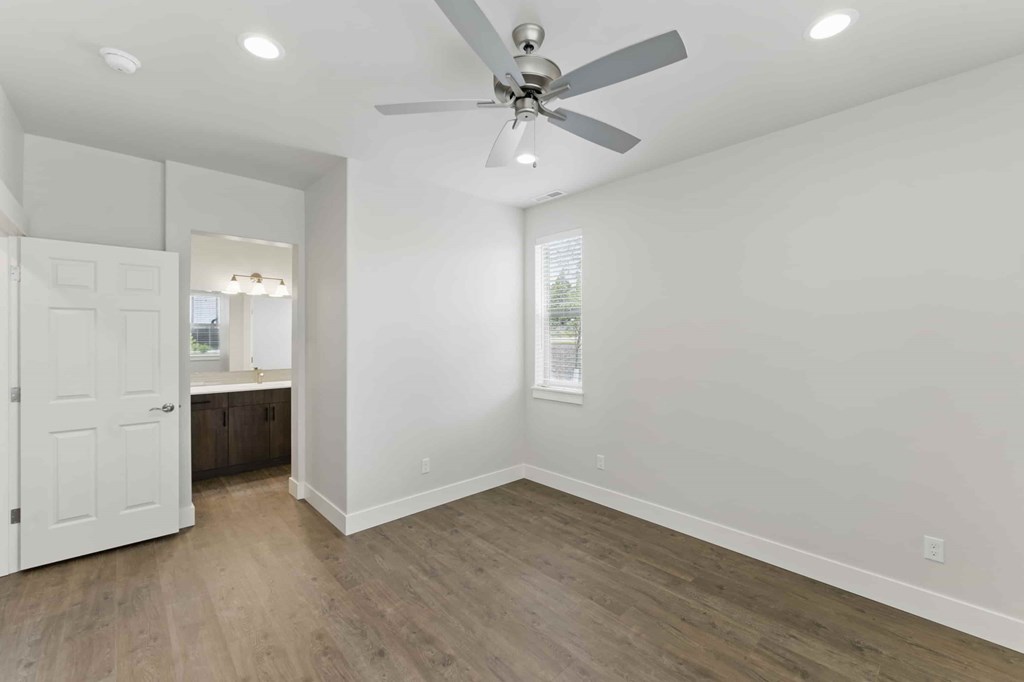 A room with a ceiling fan and wooden flooring.