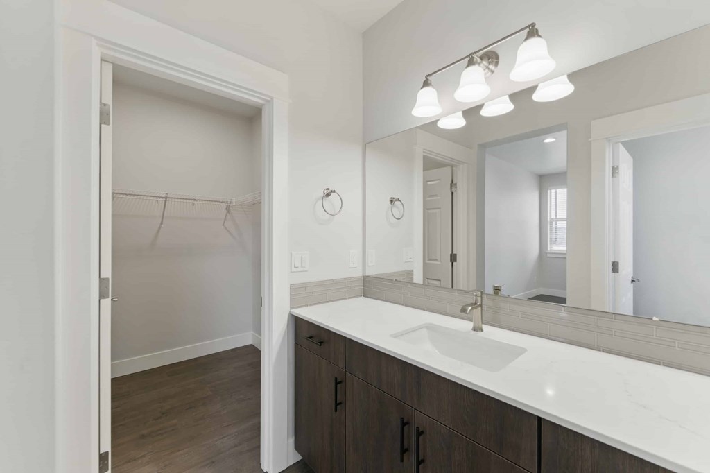 A bathroom with a sink, mirror, and a door.