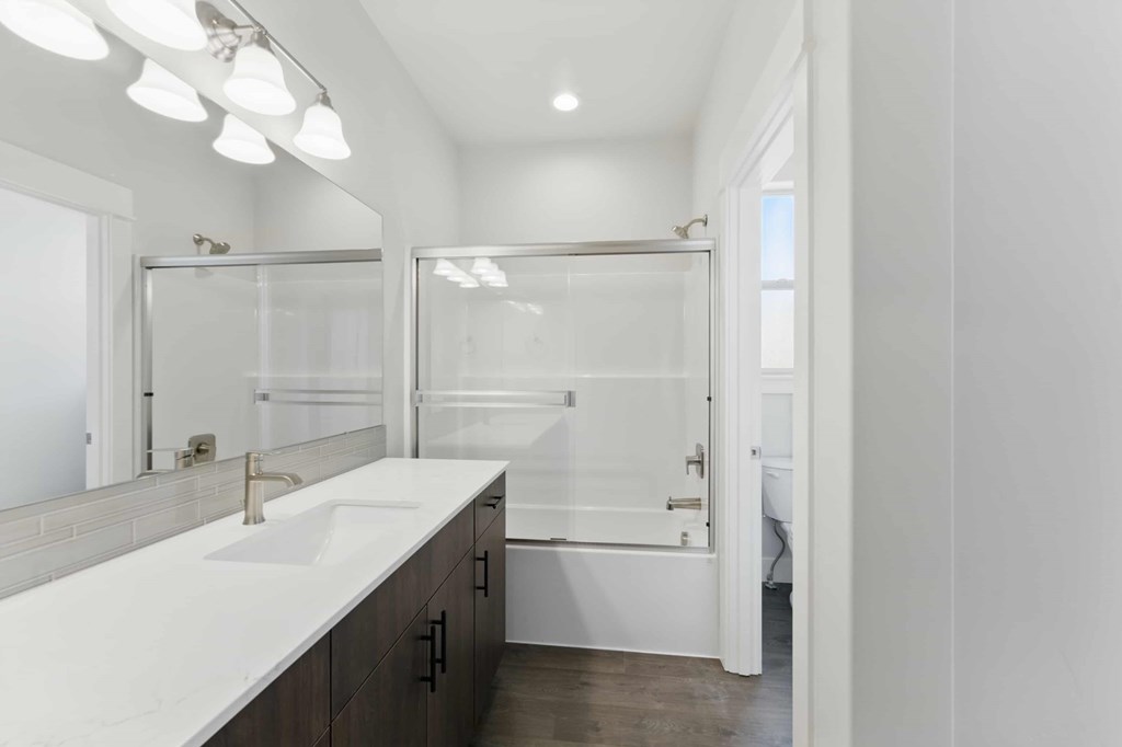 A white bathroom with a sink and a shower.