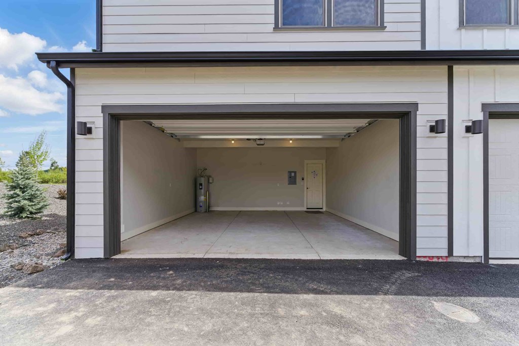 A garage door is open, revealing a clean, empty garage inside.