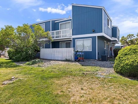 A blue house with a white fence and a green lawn.