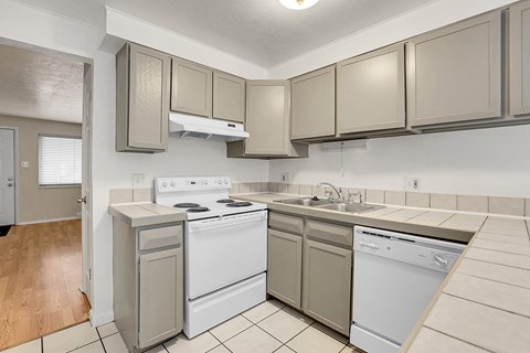 A kitchen with a white stove top oven and a white dishwasher.