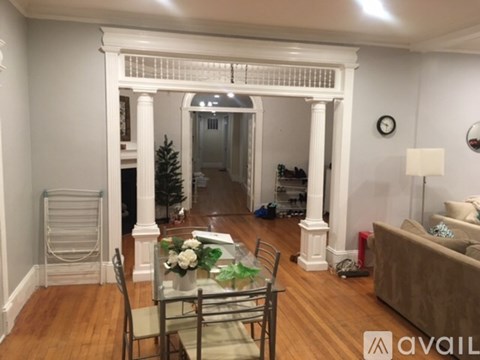 A living room with a white column and a glass table with flowers on it.