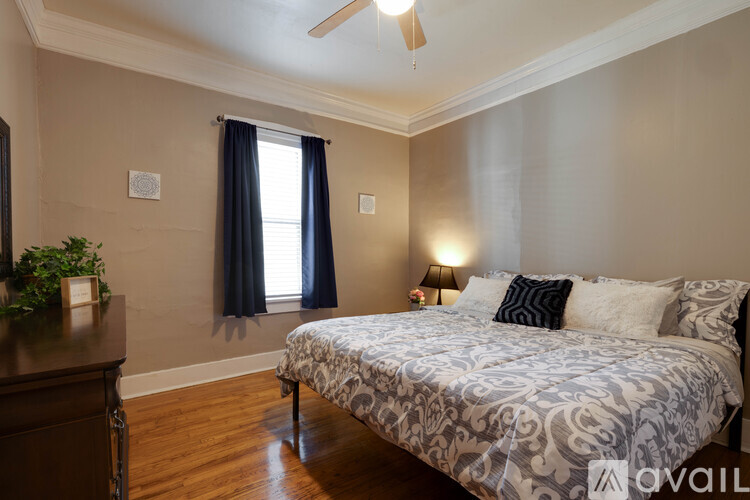 A bedroom with a bed, a ceiling fan, and a window with blue curtains.