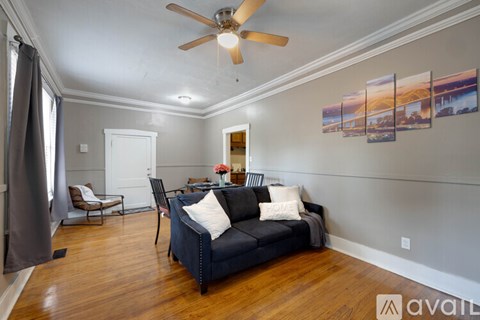 A living room with a black couch and a ceiling fan.