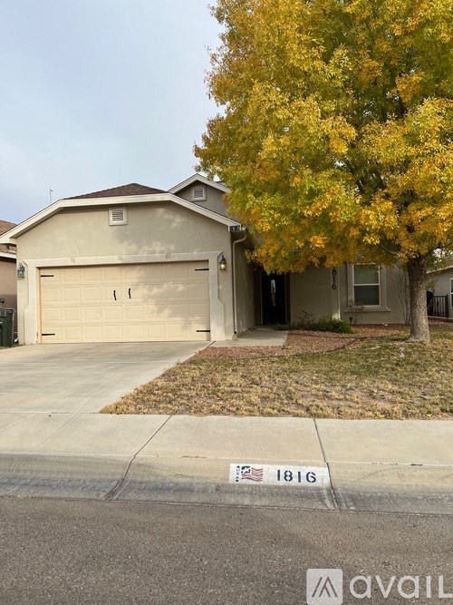 A house with a garage and a tree with yellow leaves in front of it.