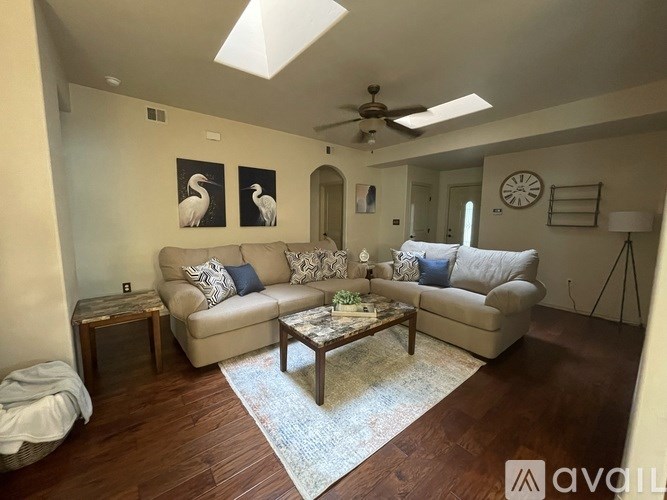 A living room with a beige couch, a coffee table, and a ceiling fan.