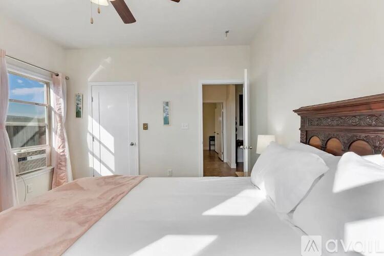 A bedroom with a large bed and a ceiling fan.