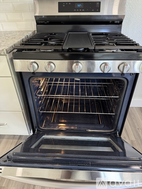 A modern black oven with the door open is in a kitchen.