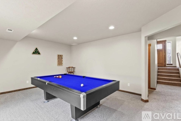 A pool table in a room with a staircase in the background.
