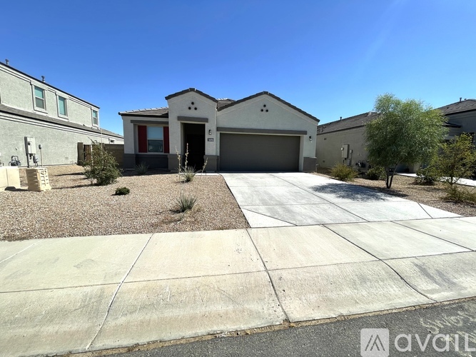 A house with a garage is surrounded by a gravel driveway and a sidewalk.