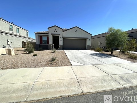 A house with a garage is surrounded by a gravel driveway and a sidewalk.