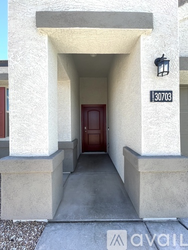 A house numbered 30703 has a red door and a concrete pathway leading to it.
