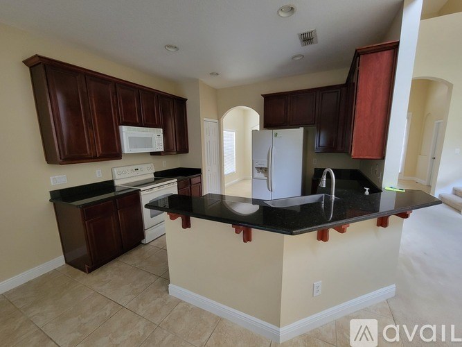 A kitchen with brown cabinets and a black countertop.