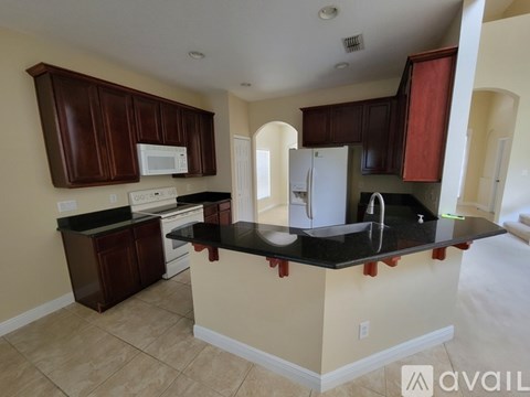 A kitchen with brown cabinets and a black countertop.