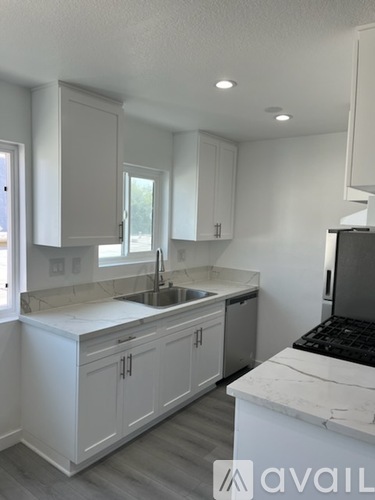A kitchen with white cabinets and a marble countertop.