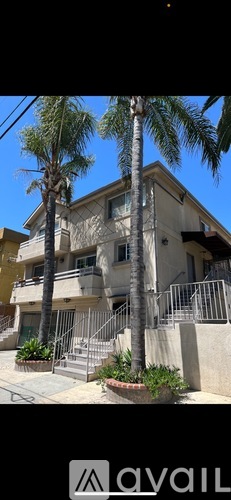 A building with a balcony and a palm tree in front.