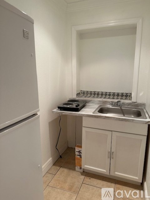 A kitchen with a white fridge, a sink, and a countertop.