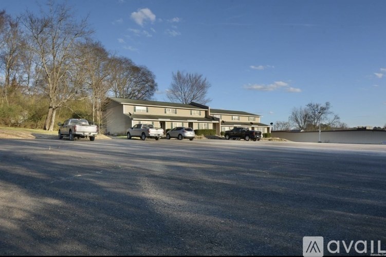 A parking lot with a building and vehicles in front.
