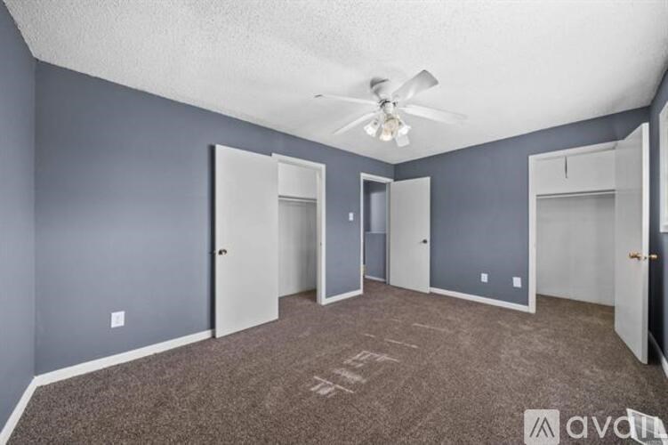 A room with grey walls and a carpeted floor with a ceiling fan.