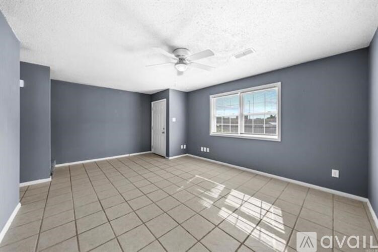 A spacious room with a ceiling fan and a window overlooking a balcony.