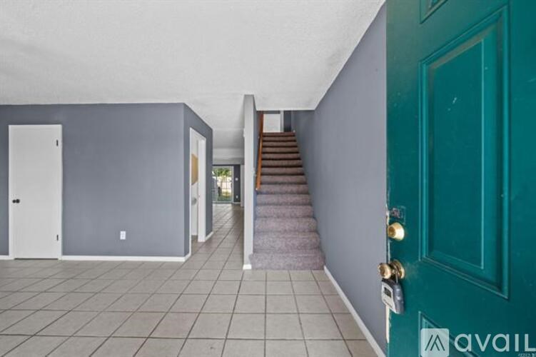 A hallway with a green door and a staircase.