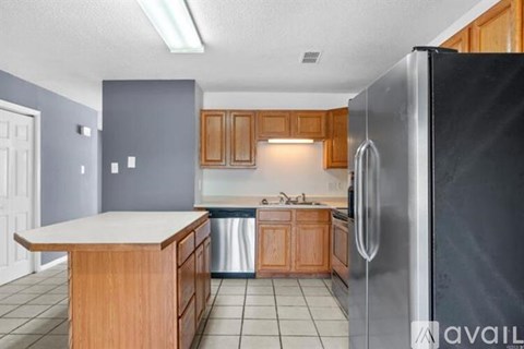 A kitchen with a black refrigerator and wooden cabinets.