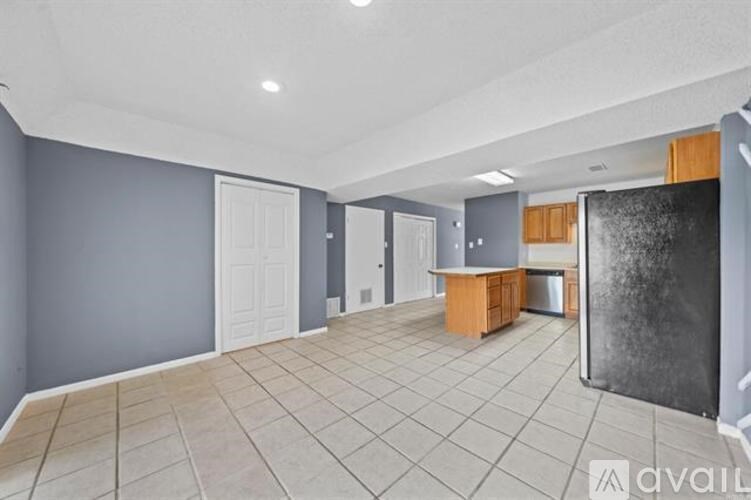A spacious room with grey walls and a kitchen area with wooden cabinets.
