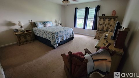 A bedroom with a bed, dresser, and chair.